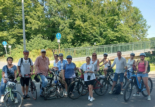 Praxisausflug 01 Mitarbeiterinnen und Mitarbeiter der Praxis machen bei einem gemeinsamen Fahrradausflug eine Pause für ein Gruppenfoto.
